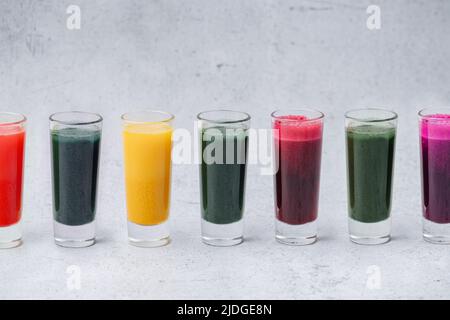 Des boissons détox maison colorées de poudre dissoute dans une rangée sur la table. Vert, orange, rouge et violet. Banque D'Images