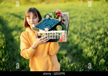 Femme avec de la nourriture fraîche sur les terres agricoles Banque D'Images
