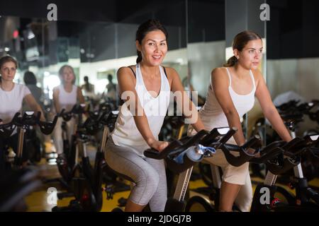 Deux femmes s'échauffent sur des vélos dans la salle de sport Banque D'Images