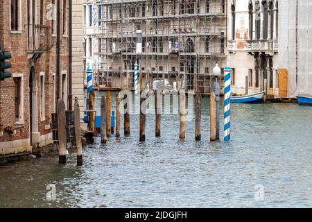 Venise, Italie - 06 09 2022: Poteaux de télécabine en bois dans le canal de Venise. Banque D'Images