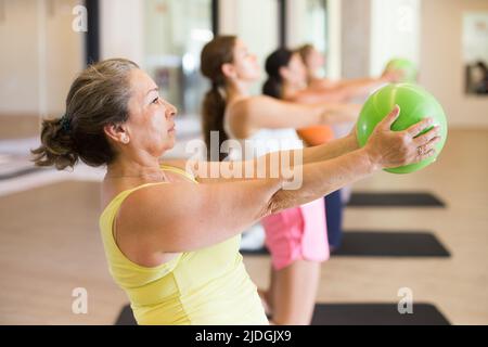 Les femmes sportives faisant des exercices avec des boules pilates pendant l'entraînement de groupe Banque D'Images