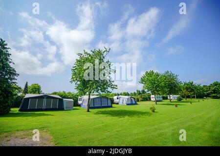 Camping avec campement de tente sur une grande pelouse verte en été Banque D'Images