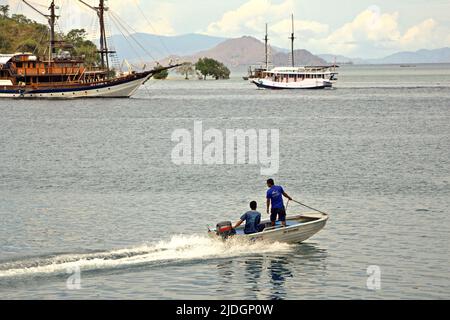 Hommes voyageant sur un bateau motorisé au large du port de Labuan Bajo à Labuan Bajo, Komodo, West Manggarai, East Nusa Tenggara, Indonésie. Banque D'Images