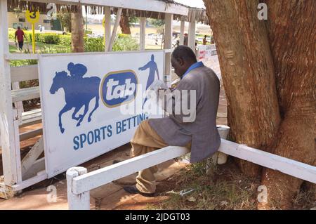 Spectateurs étudiant la cote de course, Hippodrome de Ngong, chemin Ngong, Nairobi, Kenya. 1 mars 2015 Banque D'Images