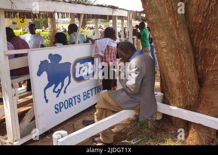 Spectateurs étudiant la cote de course, Hippodrome de Ngong, chemin Ngong, Nairobi, Kenya. 1 mars 2015 Banque D'Images