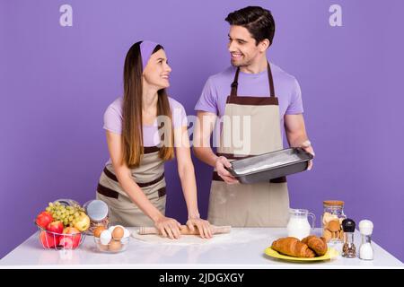 Photo de la belle dame gars préparer la recette de pâte à pizza isolée sur fond violet Banque D'Images