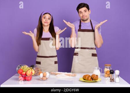 Photo de deux personnes lever les bras paumes hésiter réponse ne sais pas isolé sur fond violet de couleur Banque D'Images