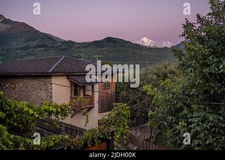 Maison géorgienne traditionnelle avec majestueuses montagnes du Caucase en arrière-plan au crépuscule à Mestia, Géorgie Banque D'Images