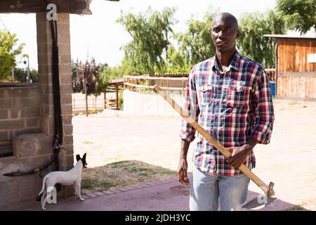 Jeune agriculteur afro-américain avec râteau debout à la ferme Banque D'Images