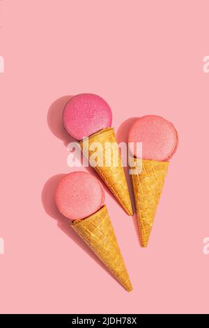 Gaufres à la crème glacée avec macarons sur fond rose. Dessert sucré, concept d'été. Lumière dure tendance, ombre sombre, vue du dessus Banque D'Images