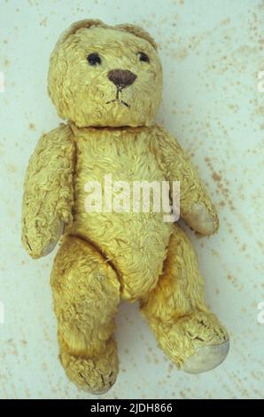 Ours en peluche vintage à fourrure jaune bien porté avec des oreilles aplaties et une triste expression sur du papier antique Banque D'Images