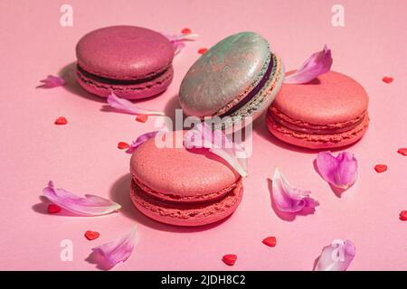 Macarons aux pétales de fleurs de pivoines sur fond rose. Dessert sucré, couleurs de bonbons colorées et pastel, concept d'été. Style romantique, carte de fête, Banque D'Images