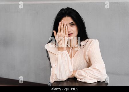 La femme géorgienne avec des timbres de pigmentation de vitiligo sur les mains couvre son visage avec ses mains. Style de vie avec les maladies saisonnières de la peau Banque D'Images