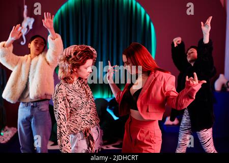 Vue latérale de deux filles dans un défi de bataille de danse à la boîte de nuit éclairée par des néons rouges Banque D'Images