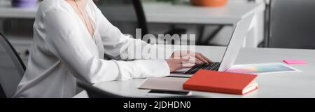 vue partielle de la femme dactylographiant sur ordinateur portable dans l'agence de publicité, bannière Banque D'Images