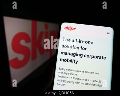 Personne tenant un téléphone portable avec la page web de la société belge de mobilité Skipr sa à l'écran devant le logo. Concentrez-vous sur le centre de l'écran du téléphone. Banque D'Images