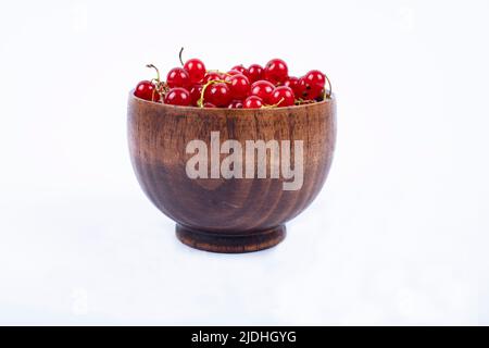 Les baies de groseilles rouges au-dessus de bol isolé sur fond blanc Banque D'Images