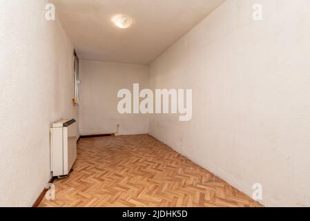 Chambre vide avec parquet en chêne à chevrons et menuiserie de bois et accumulateur de chaleur sur le mur Banque D'Images