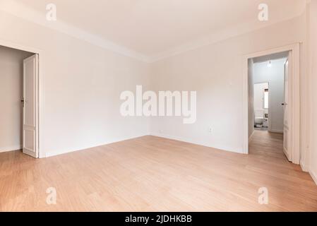 Chambre vide avec parquet en chêne, murs peints en blanc et boiseries blanches et salle de bains dans une autre chambre Banque D'Images