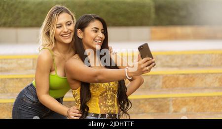 Deux jeunes femmes latines prenant un selfie dans un escalier dans la ville concept amitié Banque D'Images