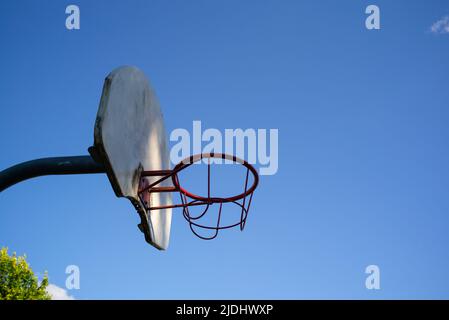 Panier de basket-ball en métal et planche contre un ciel bleu sans nuages avec espace de copie. Éclairé par la lumière du soleil. Banque D'Images