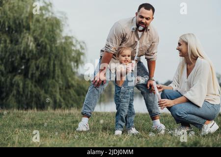 Portrait de Happy Young Family, maman et papa avec leur petite fille qui s'amusent à l'extérieur de la ville Banque D'Images