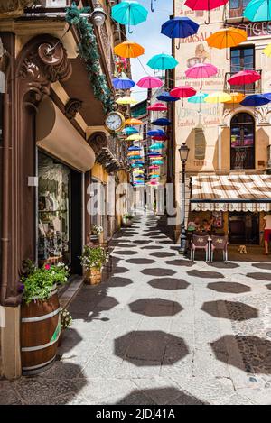 Des parasols colorés protègent les passants sur la Piazza Lamarmora entourée de maisons historiques dans la vieille ville d'Iglesias, dans le sud-ouest de la Sardaigne, en Italie Banque D'Images