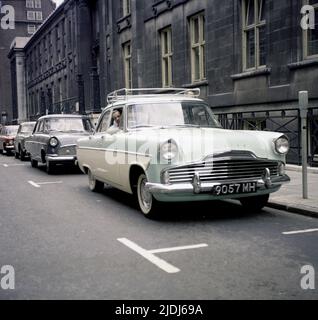 1964, historique, un homme assis dans sa voiture de l'époque, un ton, British Ford Zodiac, garée dans une rue, Angleterre, Royaume-Uni. Banque D'Images