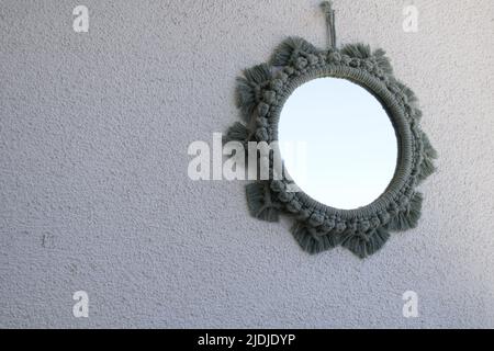 Miroir en macrame sur fond blanc, miroir en macrame vert, décoration murale, décoration de balcon adaptée à la saison estivale. Banque D'Images