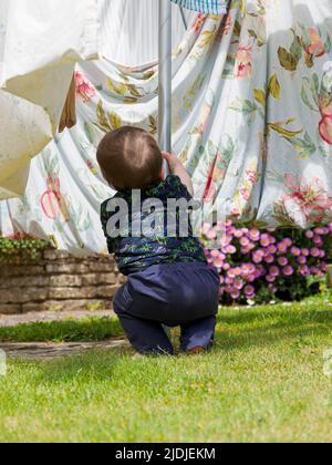 Un tout-petit qui monte sur le poteau de la ligne de lavage dans le jardin, Royaume-Uni Banque D'Images