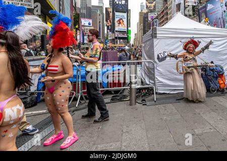 New York, États-Unis. 21st juin 2022. Un mendiant sans-abri et des femmes vêtues de peu d'argent essaient de gagner de l'argent de passants, à côté de personnes participant à un cours de yoga gratuit dans le Times Square de New York City pour célébrer la septième Journée internationale du yoga. Credit: Enrique Shore/Alay Live News Banque D'Images