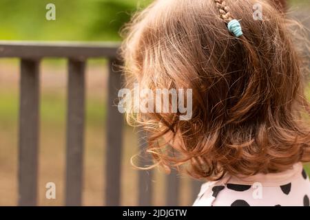 Petite fille aux cheveux rouges sur fond de tourniquet dans un parc d'été Banque D'Images