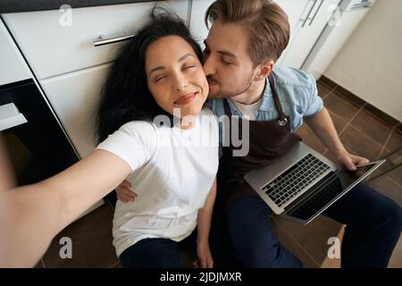 Couple romantique prenant des selfies au sol de la cuisine Banque D'Images