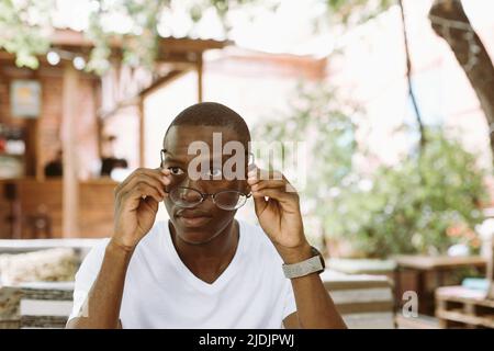 Gros plan fatigué et fatigué multiracial, homme de peau sombre qui a retiré ses lunettes, la lentille de contrôle. Problème de vision et de vision Banque D'Images