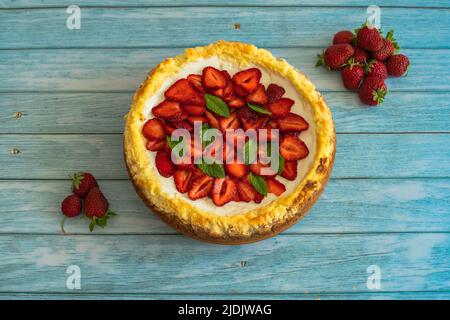 Gâteau maison aux fraises sur une table en bois.délicieux cheesecake avec des fraises décorées de feuilles de menthe.vue du dessus.fruits d'été biologiques sains Banque D'Images