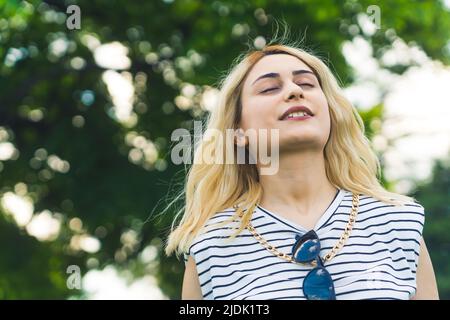 Blonde caucasienne fille appréciant l'air frais en été. Moyenne gros plan naturel vert. Photo de haute qualité Banque D'Images