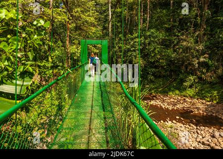 Pont suspendu vert au Costa Rica pour permettre aux randonneurs de traverser un petit ruisseau ou un ruisseau qui coule sous le pont. Banque D'Images