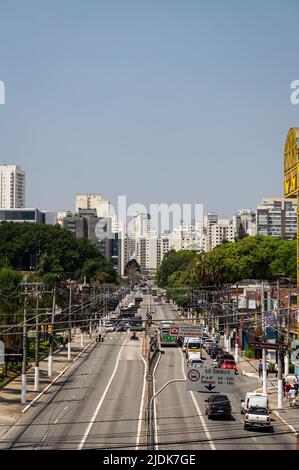 Circulation de jour d'affaires passant par les deux voies de l'avenue Francisco Matarazzo dans le quartier d'Agua Branca avec beaucoup de gratte-ciel à l'arrière sous le ciel ensoleillé. Banque D'Images