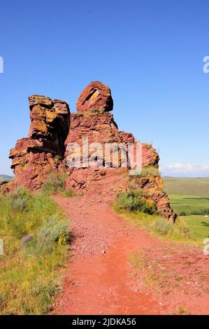 Le chemin le long du sommet de la colline à une formation inhabituelle de pierre rouge. Coffres de montagne, Khakassia, Sibérie, Russie. Banque D'Images