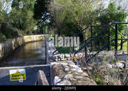 défense contre les inondations avec des murs de roche et des arbres sur le côté et l'eau s'inonde et danger d'eau profonde signe Banque D'Images