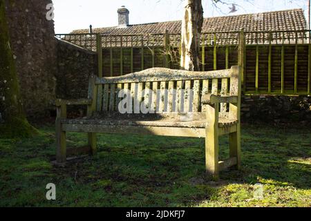 ancien banc de parc recouvert de lichen avec clôture et tuiles de toit en arrière-plan Banque D'Images