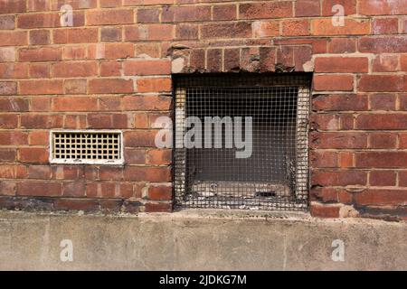 briques d'air blanc et barbecue en métal dans un mur de briques rouges avec le pavé au premier plan Banque D'Images