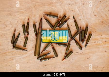 Pili se trouve sur un fond en bois et à côté se trouve un timbre avec le drapeau de l'Ukraine, la guerre en Ukraine, les munitions et les armes Banque D'Images