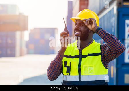 Travailleur noir ingénieur de travail africain contremaître le contrôle radio dans la cour de conteneurs de fret portuaire Banque D'Images