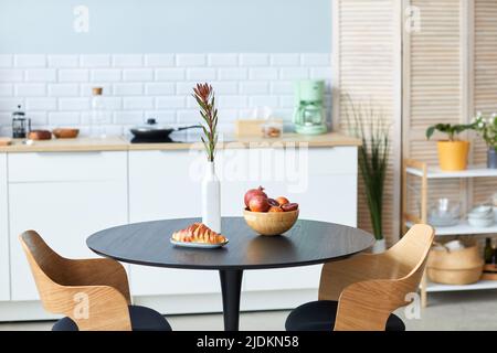 Gros plan de fruits et croissants sur une table et des chaises élégantes en bois avec détail noir dans un minimum d'intérieur de cuisine, espace de copie Banque D'Images