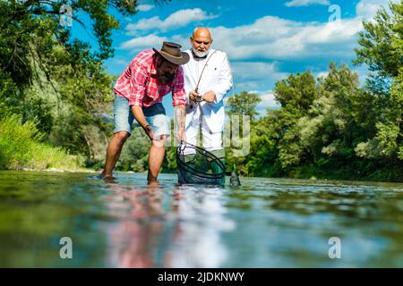 Pêcheurs hommes amis et truite trophée. Père et fils de pêche. Générations hommes pêche dans la rivière. Banque D'Images