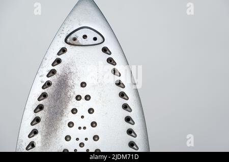 Semelle endommagée du fer, taches brunes et traces de brûlure avec de la fumée et de la vapeur. Comportement incorrect lors du repassage des vêtements. Banque D'Images