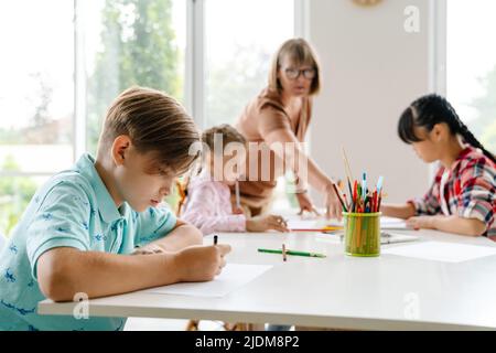 Enseignante mature parlant avec ses élèves pendant la classe à l'intérieur de l'école d'art Banque D'Images