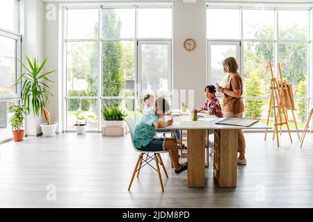 Enseignante mature parlant avec ses élèves pendant la classe à l'intérieur de l'école d'art Banque D'Images