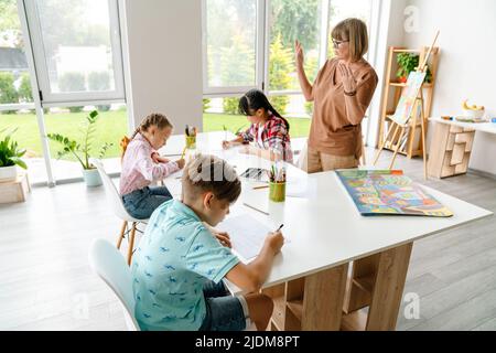 Enseignante mature parlant avec ses élèves pendant la classe à l'intérieur de l'école d'art Banque D'Images